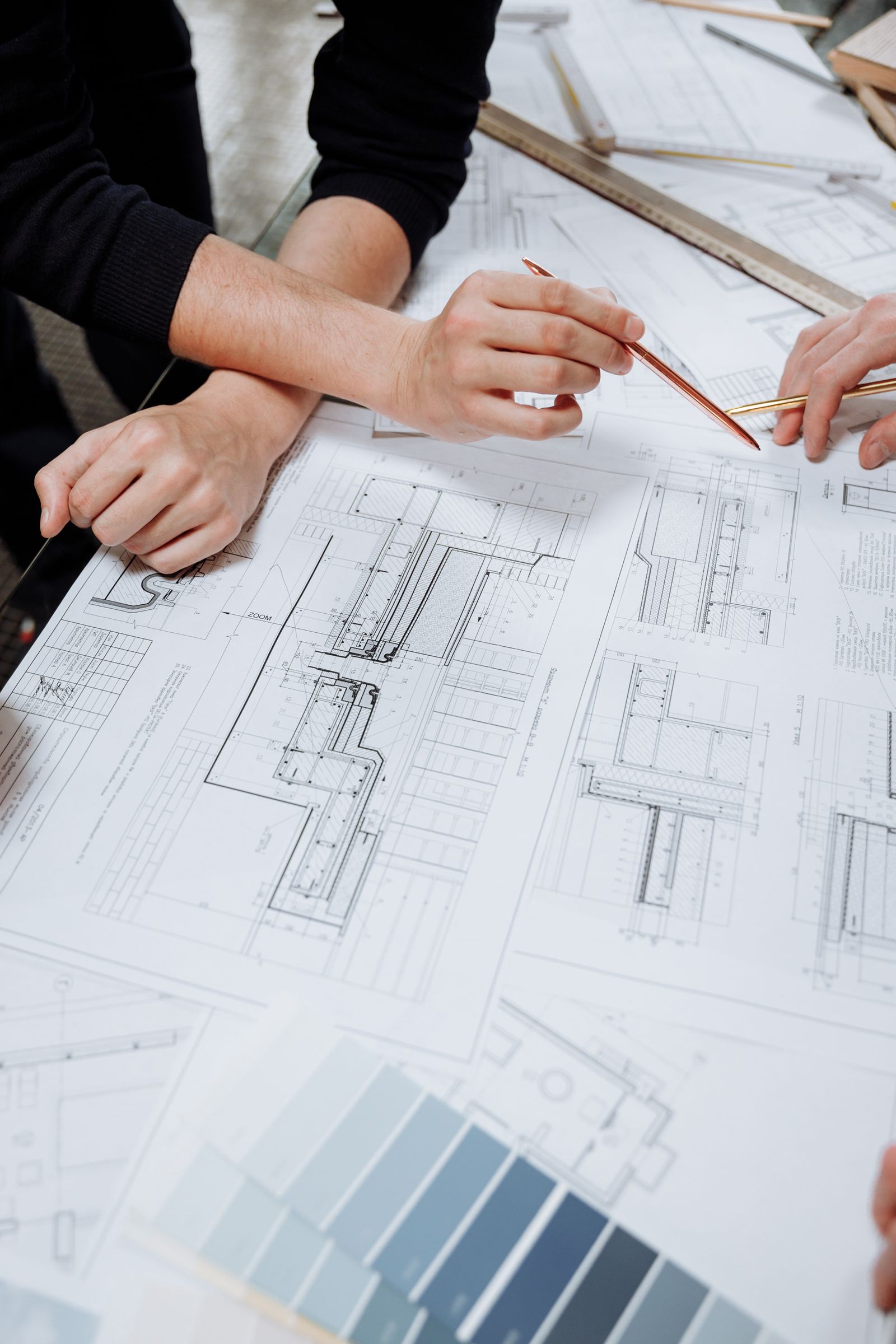Two estimators reviewing construction blueprints together at a table.
